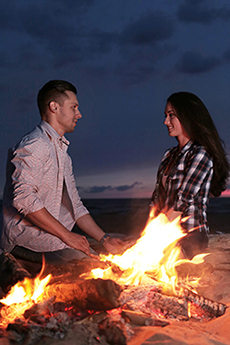 picture of a couple next to a fire on a beach